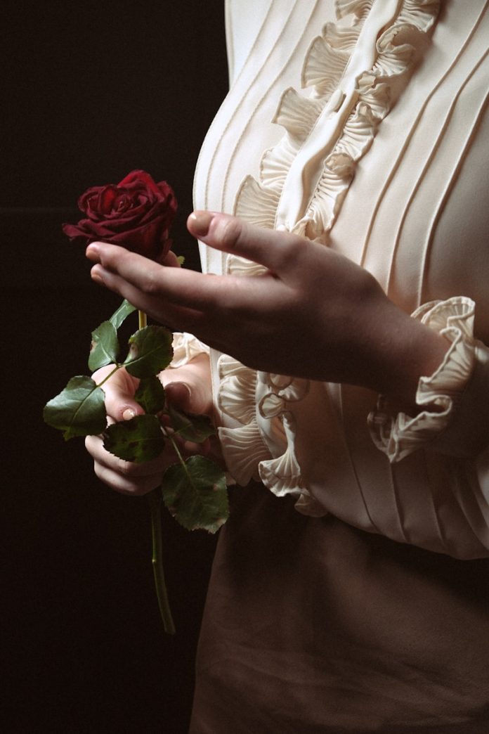 a woman holding a rose in her hand