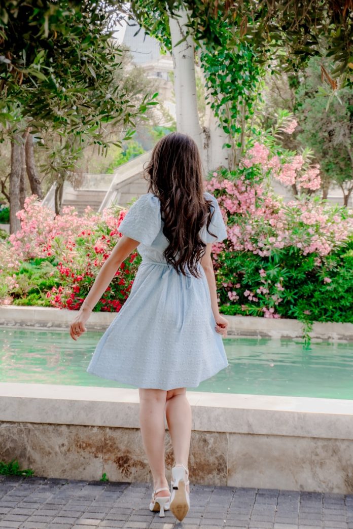 Woman in blue dress by a fountain with flowers