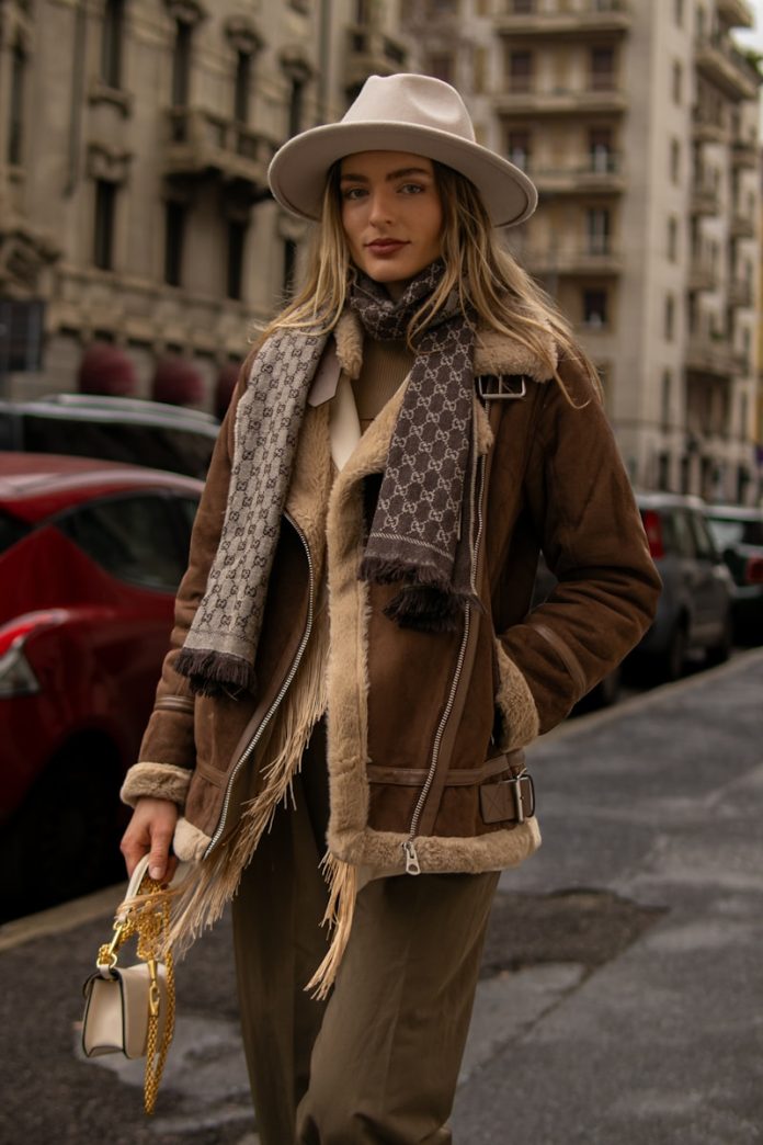 A woman in a hat and coat is walking down the street