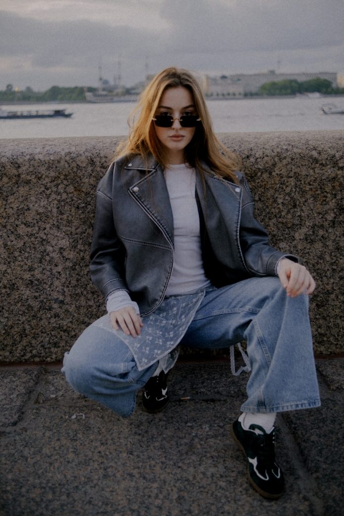 Young woman in sunglasses and leather jacket crouching
